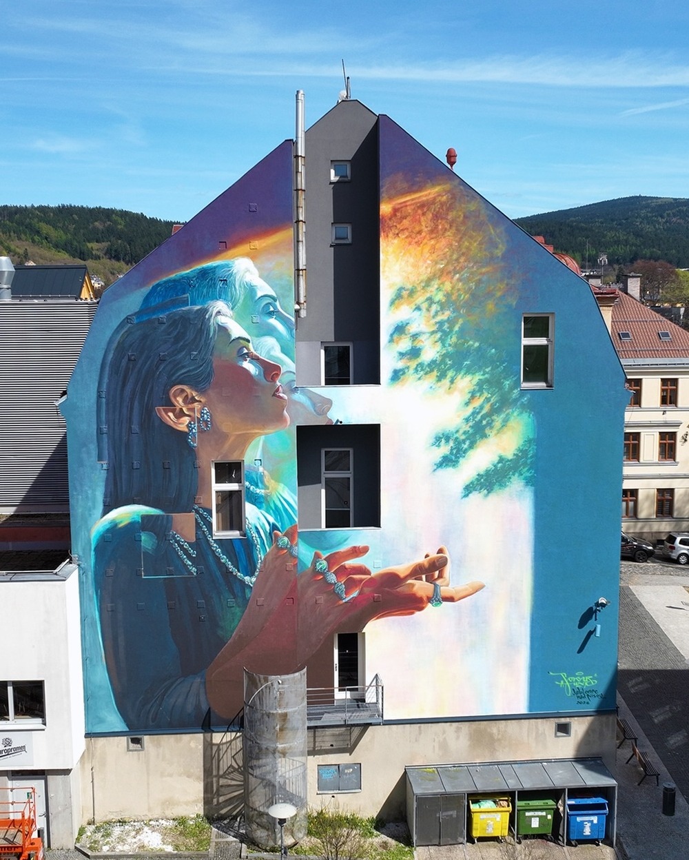 Tvář města mural by Sokar Uno in Jablonec nad Nisou, showing a woman lifting her hands toward a burst of light.